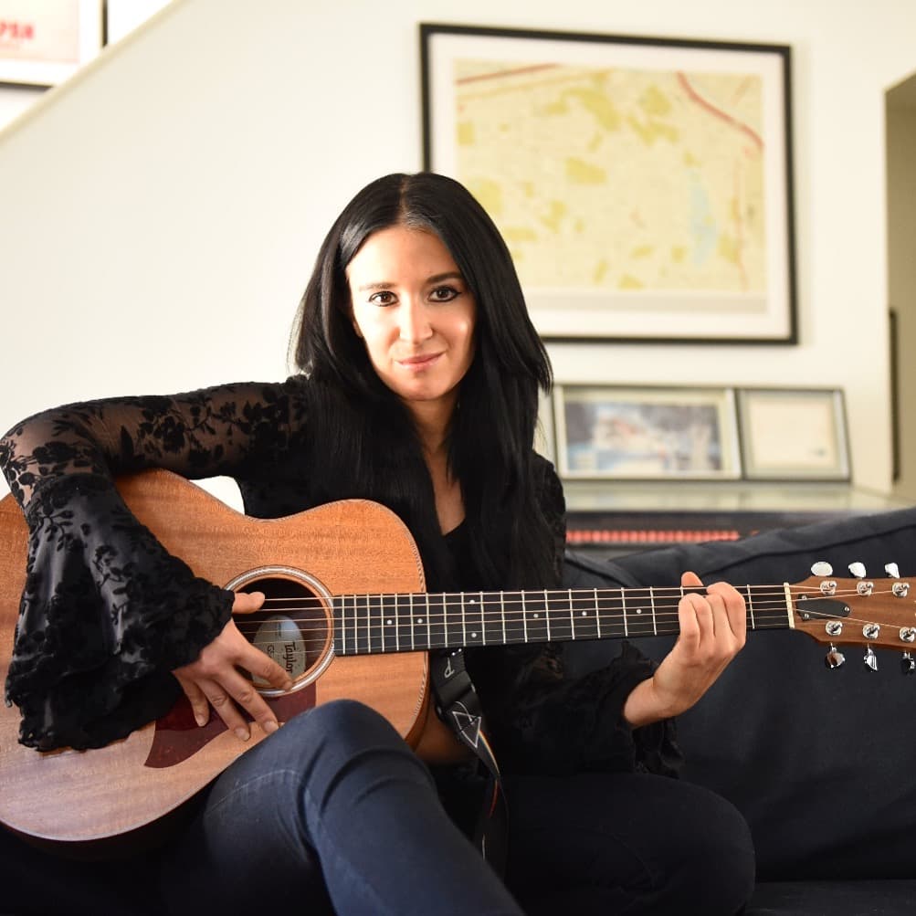 Jackie holding a Taylor acoustic guitar — acoustic duo configuration.