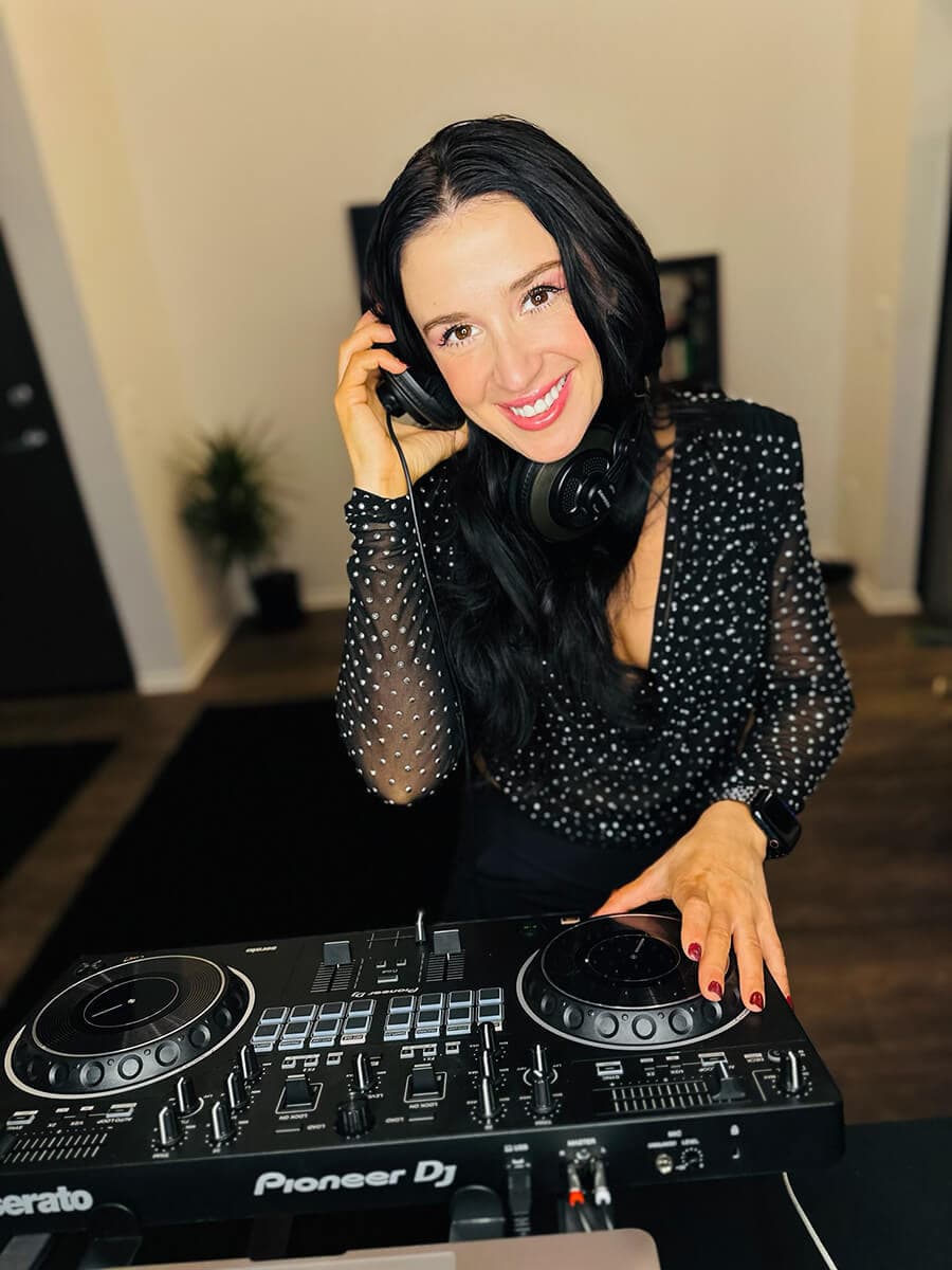 Jackie smiling behind her Pioneer DJ controller in a clean white studio.
